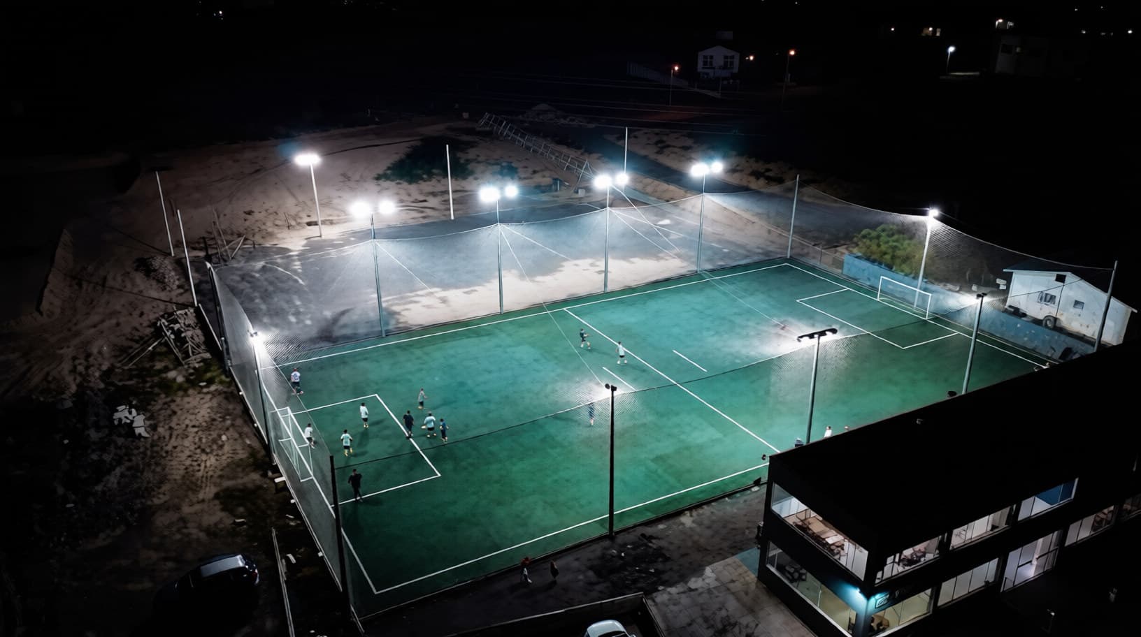 Vista aérea noturna da quadra de grama sintética da Arena Maestro iluminada